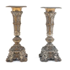 Two finely crafted silver and gold metal columns with geometric motifs and four masks at the base. Dated 1883